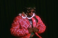 a man in a red jacket standing in front of a dark room